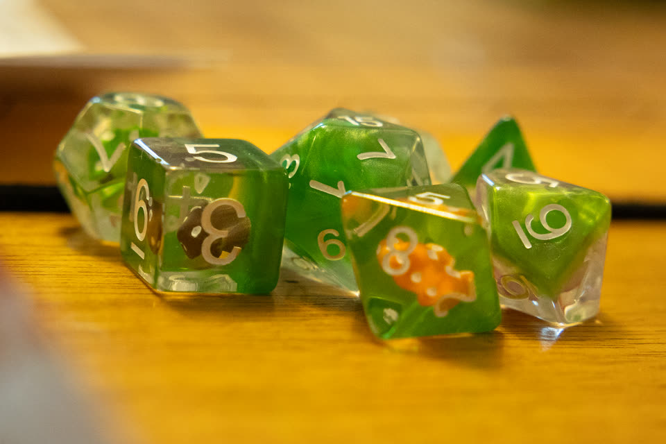Close-up of a set of translucent green dice on the wooden table